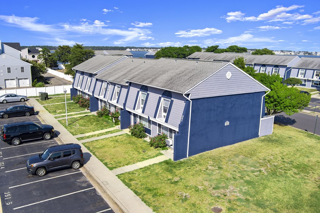 a blue house with a gray roof and a parking lot