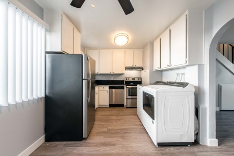 a kitchen with white cabinets and a black refrigerator and a washing machine