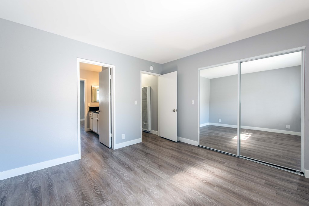 Master bedroom with view of mirrored closet doors and entrance to the hallway and bathroom