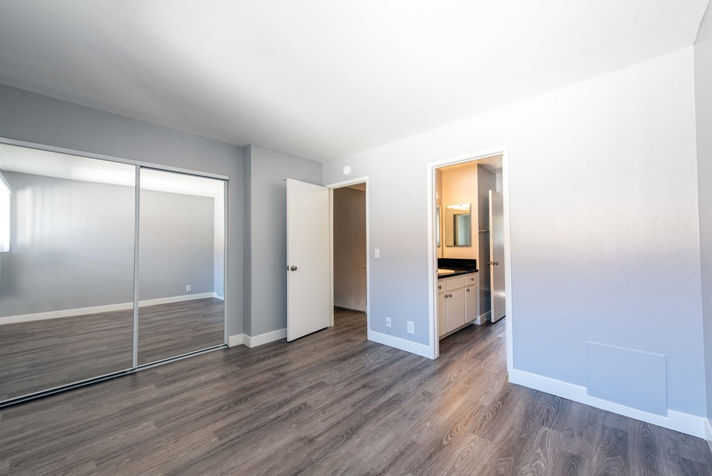 Master bedroom with wood flooring with master bathroom