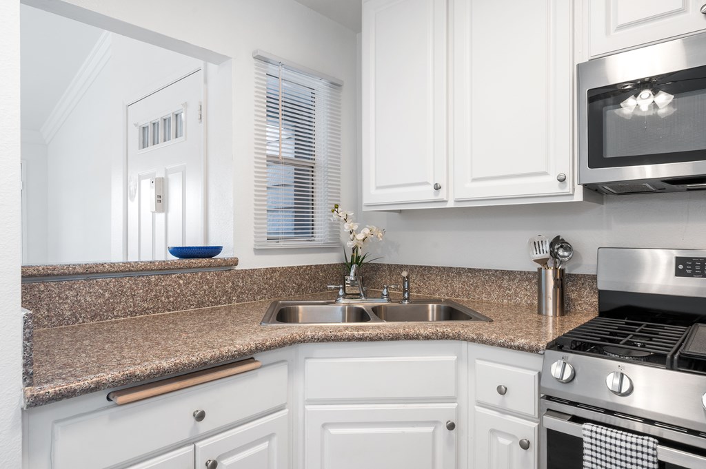 A kitchen with white cabinets and a granite countertop.