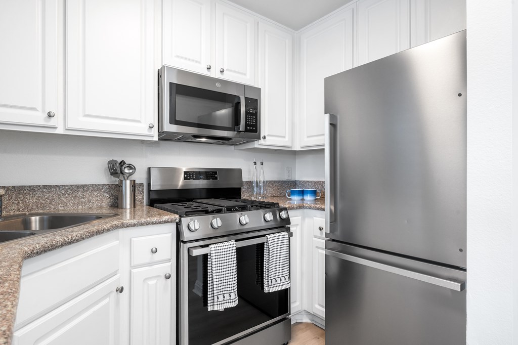 A kitchen with a stove, microwave, and refrigerator.