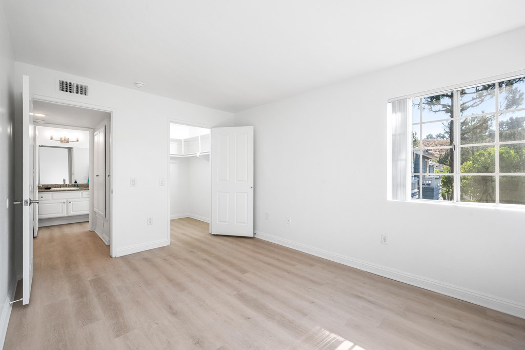 A spacious, empty room with white walls and a large window.