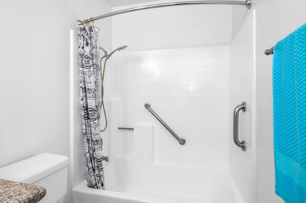 A white bathroom with a shower curtain and a blue towel.