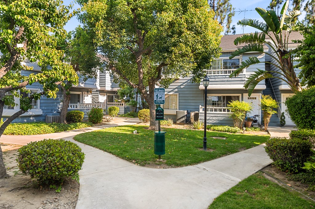 A residential grassy  area with a pathway and a green post.