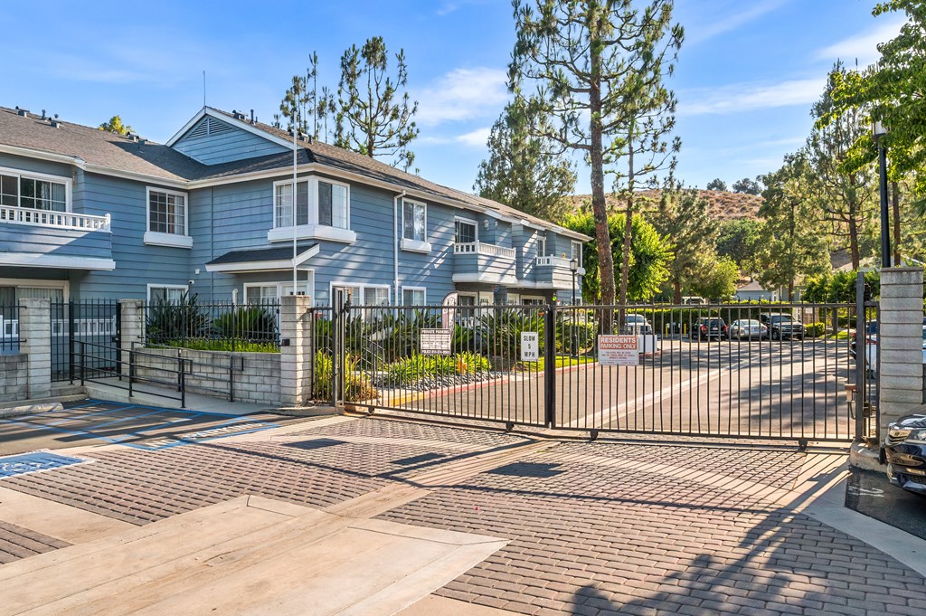 A gated entrance to a residential complex with a blue building.