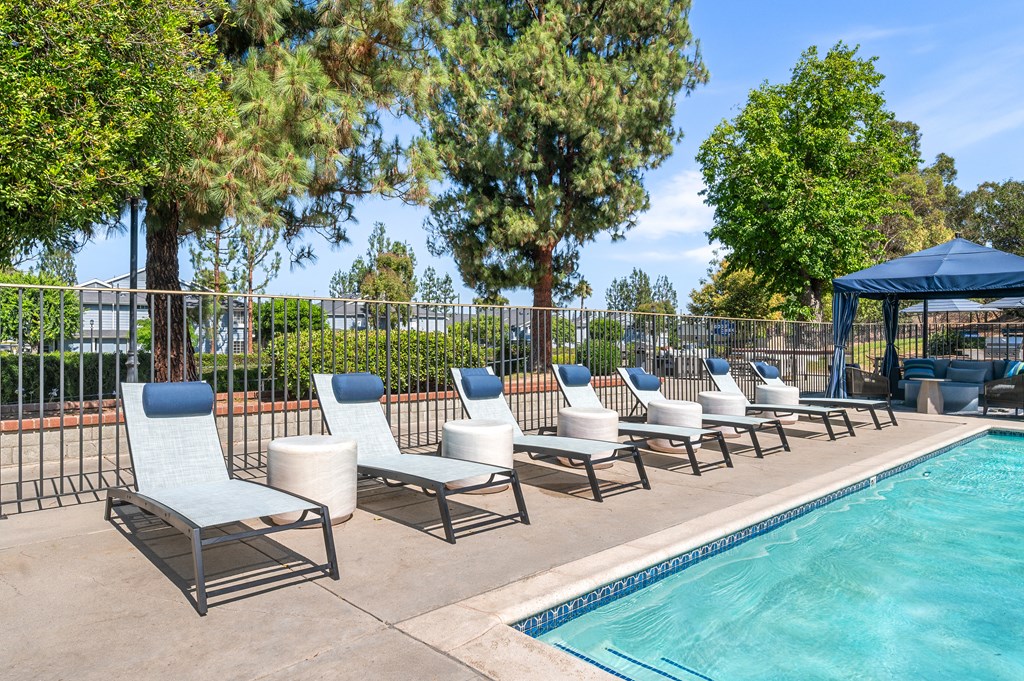 A row of lounge chairs by the pool the edge of a pool.