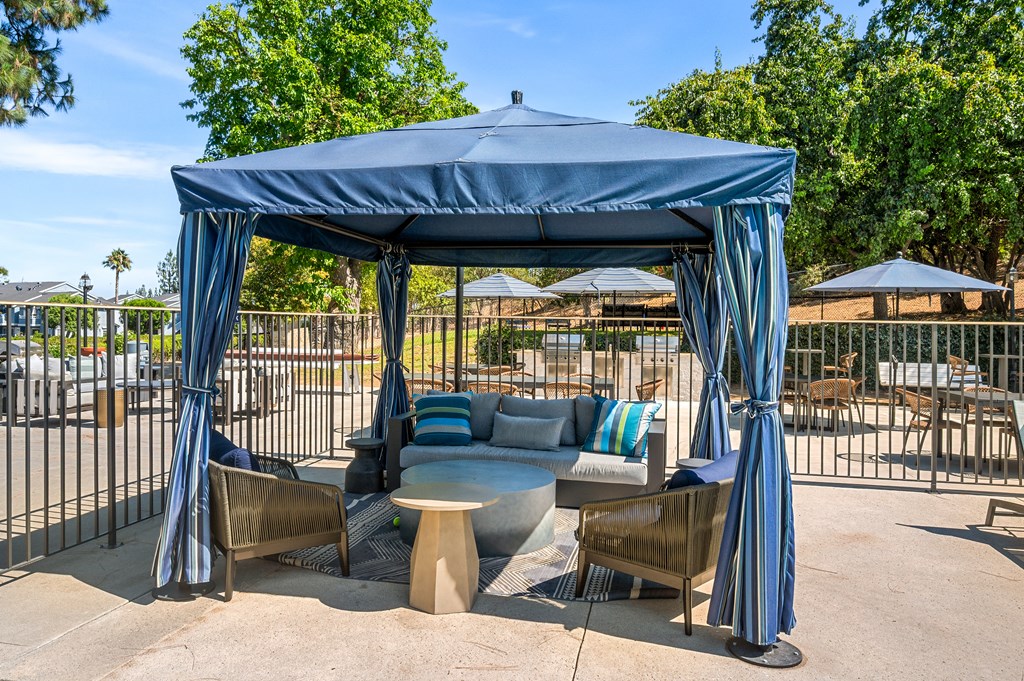 A blue cabana with striped umbrellas and a couch inside.