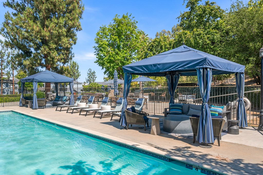 A pool area with a blue canopy and lounge chairs.