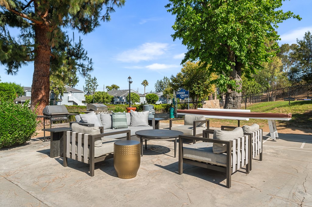 A patio seating area with a table and chairs surrounded by trees.