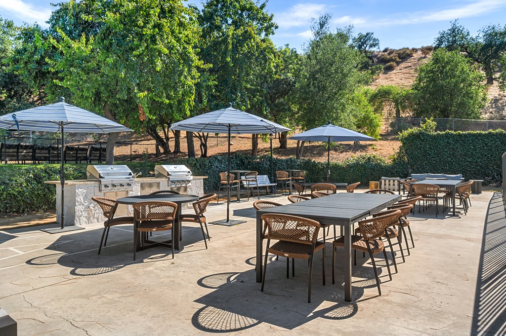 A patio with tables and chairs under umbrellas.