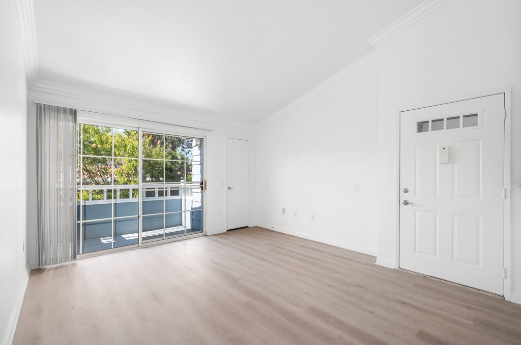 A room with a sliding glass door leading to a balcony.