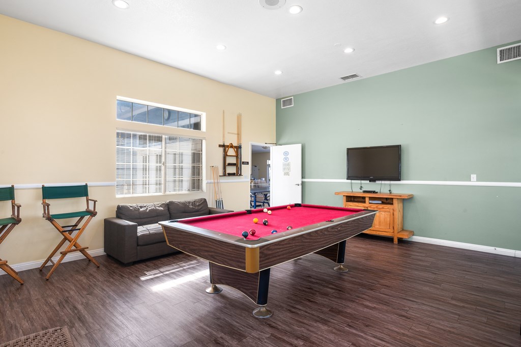 A room with a pool table and a television.