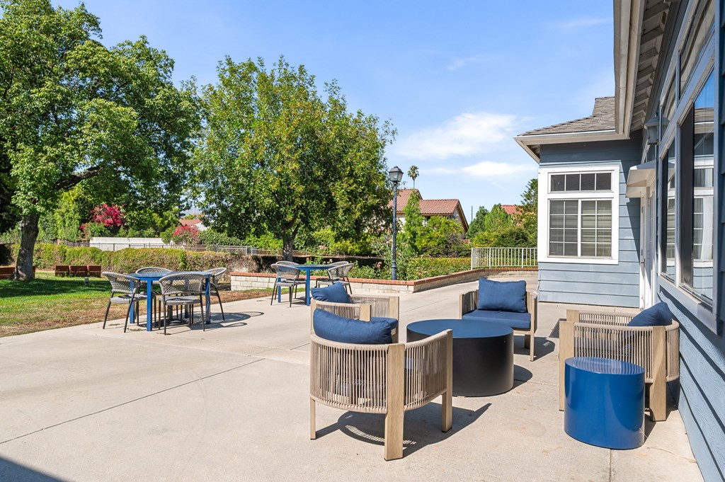 A patio with a table and chairs is surrounded by trees.