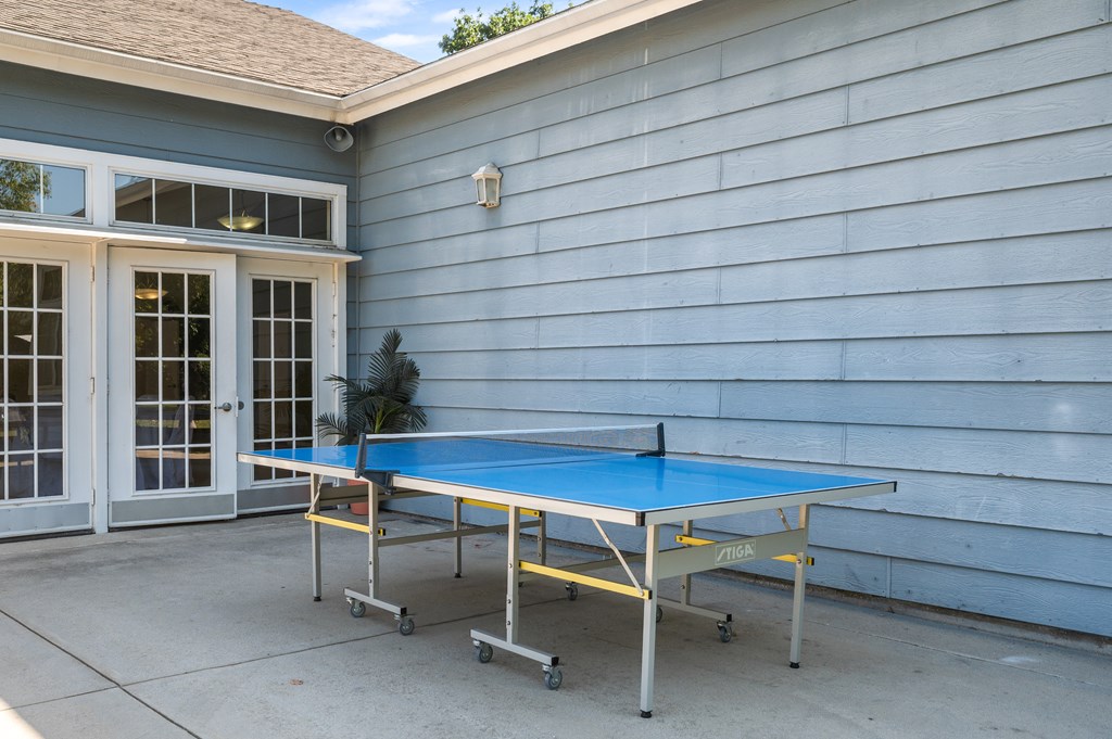 A blue ping pong table is set up on a patio.