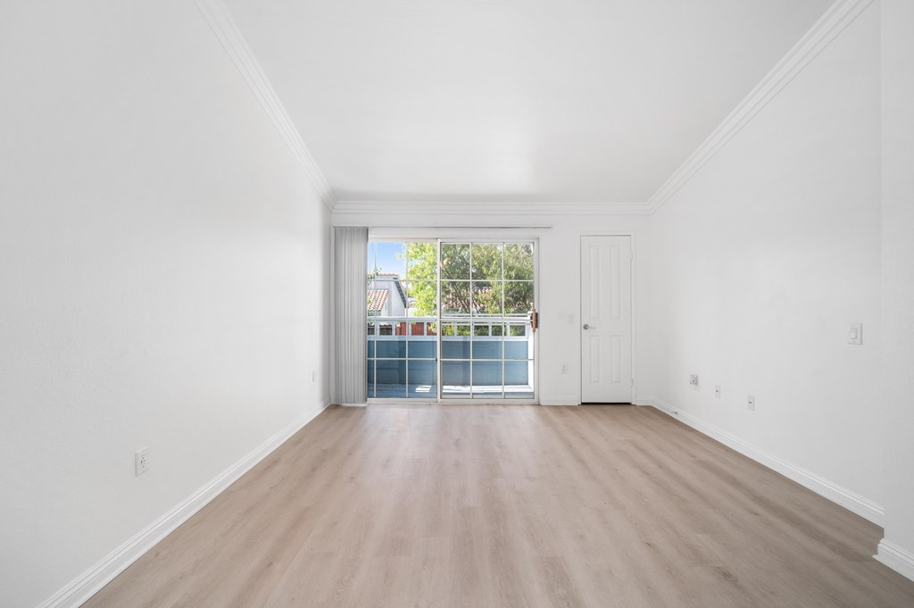 A room with a sliding glass door leading to a balcony.