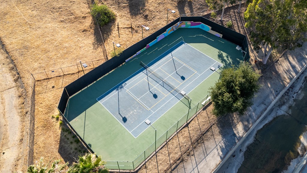 An aerial view of a tennis court surrounded by a fence.