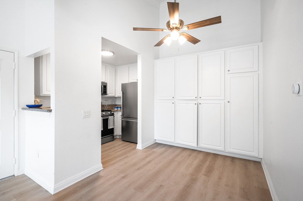 A kitchen with white cabinets and a ceiling fan.