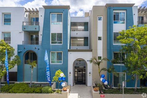 A modern apartment building with balconies and a blue and white facade.