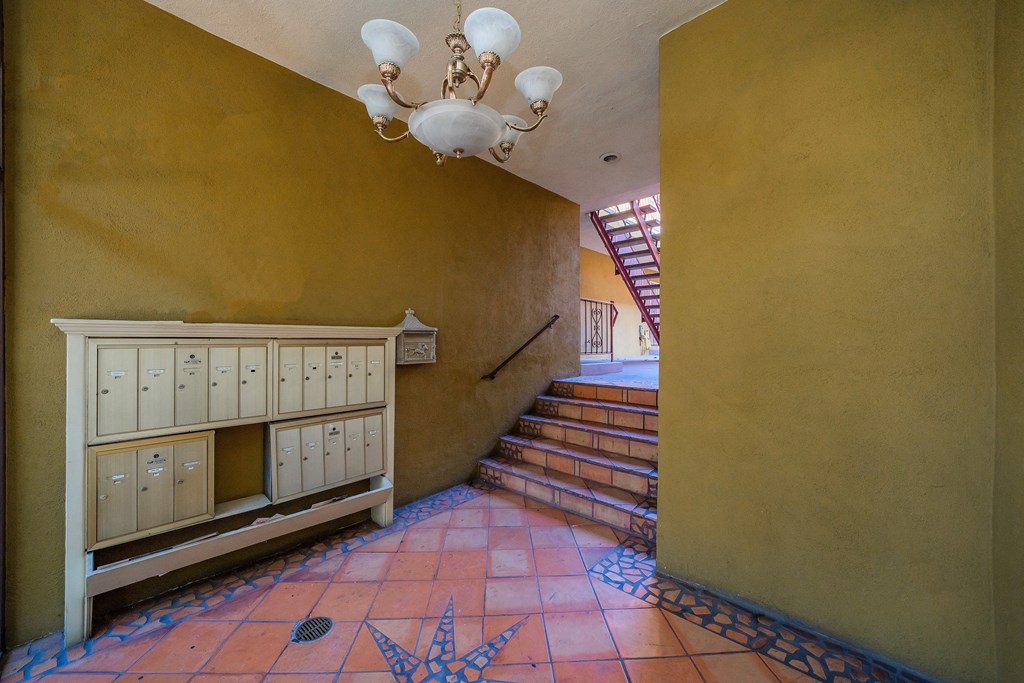 a hallway with a staircase and a yellow wall and a chandelier