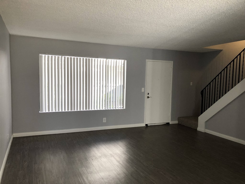 A room with a staircase and a window with blinds.