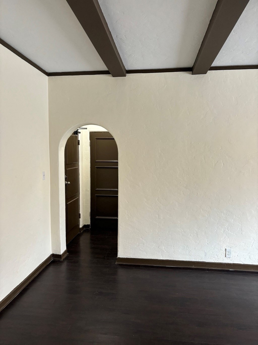 an empty room with white walls and a dark wood floor