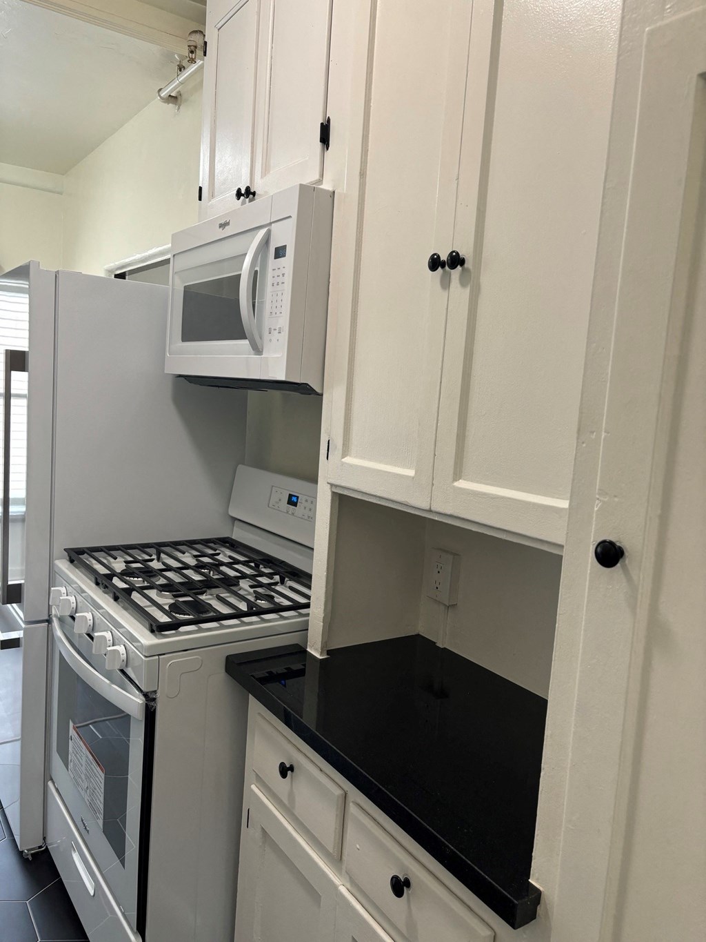 a small kitchen with white cabinets and a stove and microwave