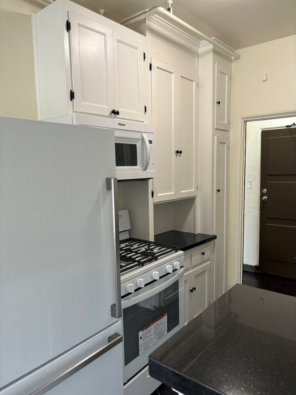 a small kitchen with white cabinets and a stove and microwave
