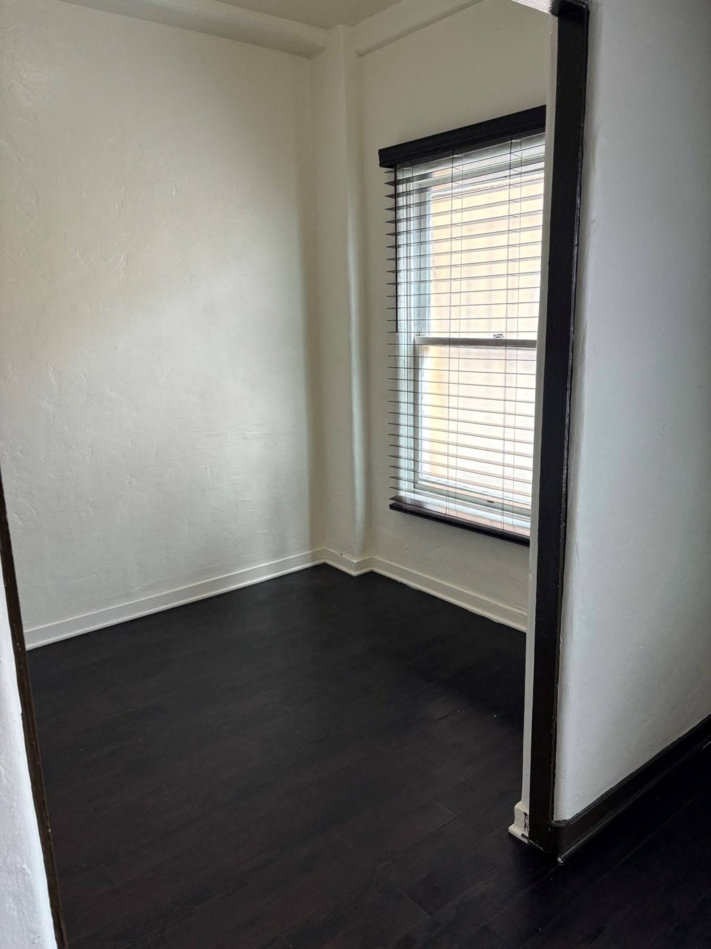 an empty room with wood floors and a window