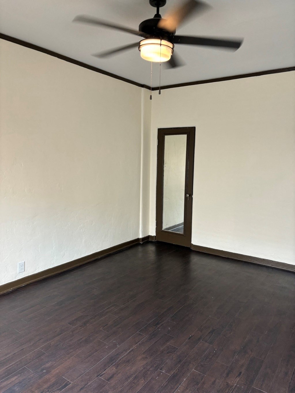 an empty living room with wooden floors and a ceiling fan
