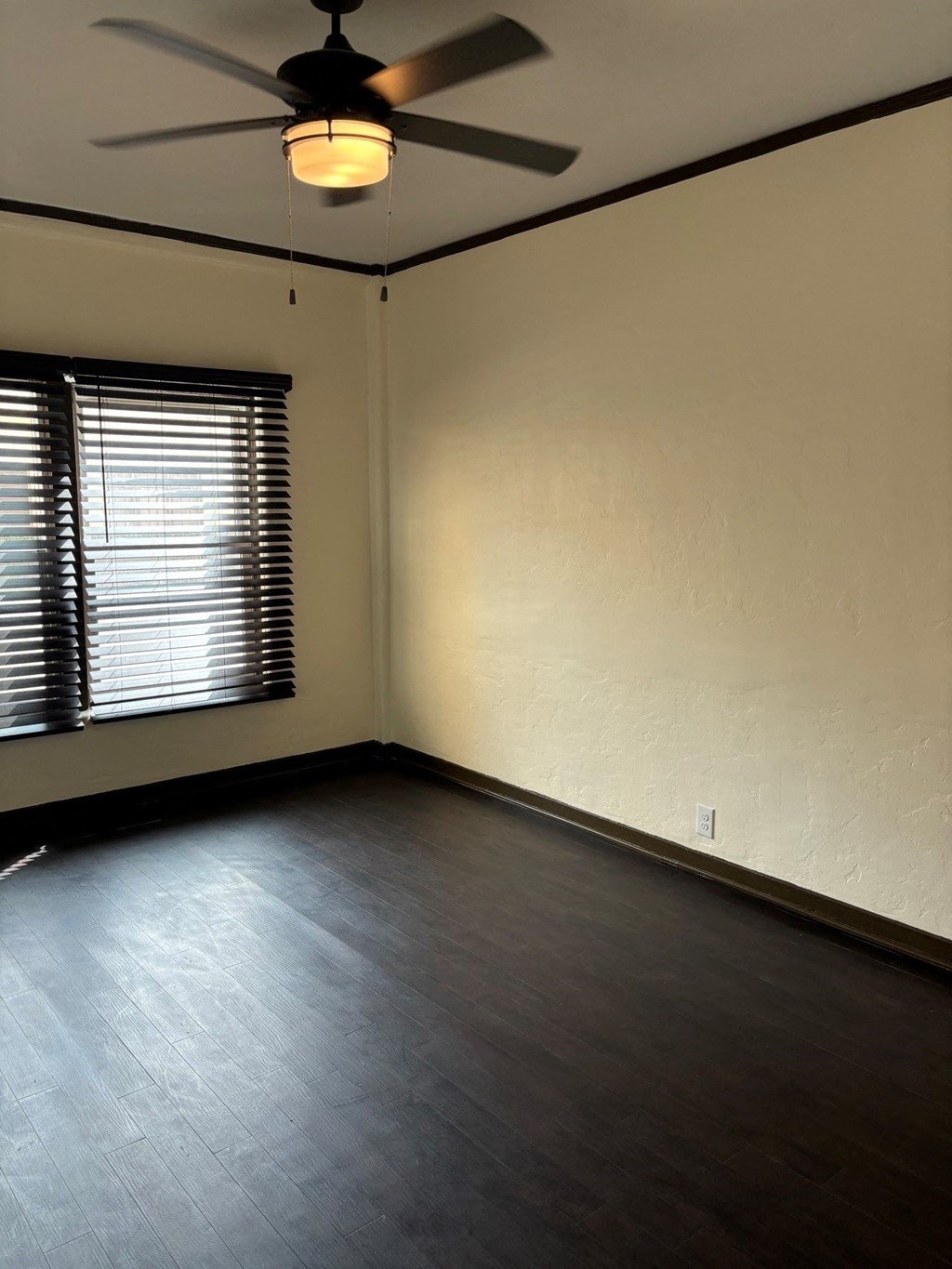 an empty room with a window and a ceiling fan