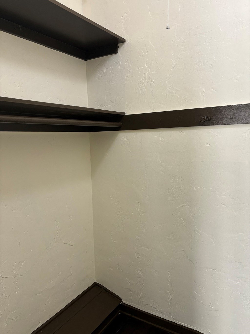 the corner of a room with white walls and a black shelf