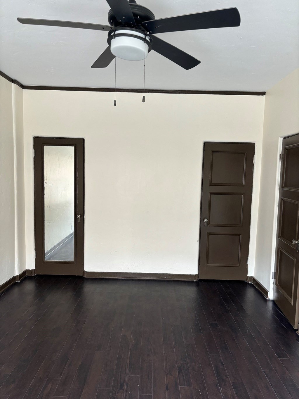 an empty living room with wooden floors and a ceiling fan