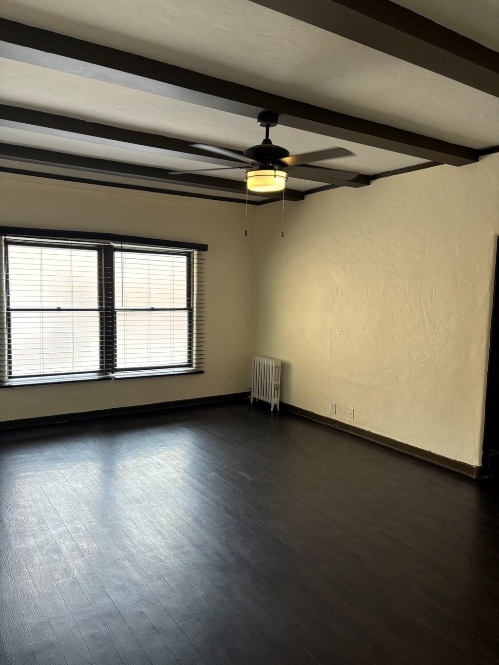an empty living room with a ceiling fan and a window
