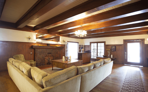 A large beige couch sits in a spacious living room with wooden floors and a fireplace.