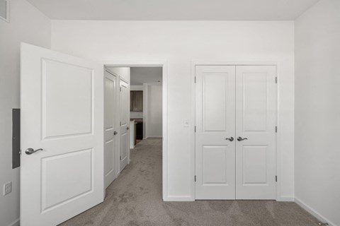 A hallway with white doors and carpeted floors. at Heritage at Mount Holly, Mount Holly, New Jersey