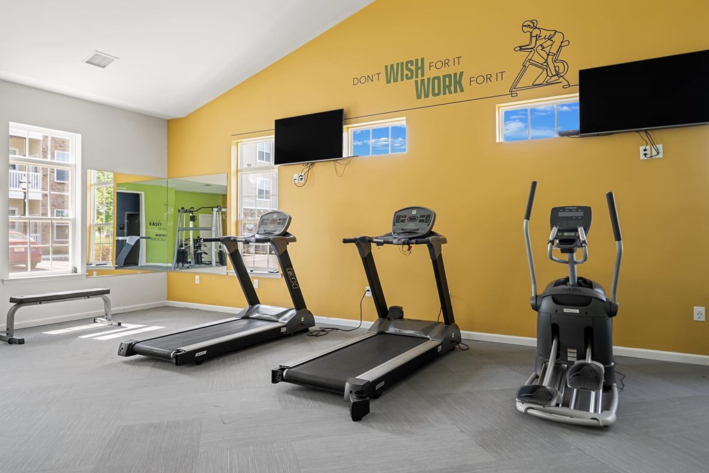 A gym with treadmills, elliptical machines, and a motivational poster.