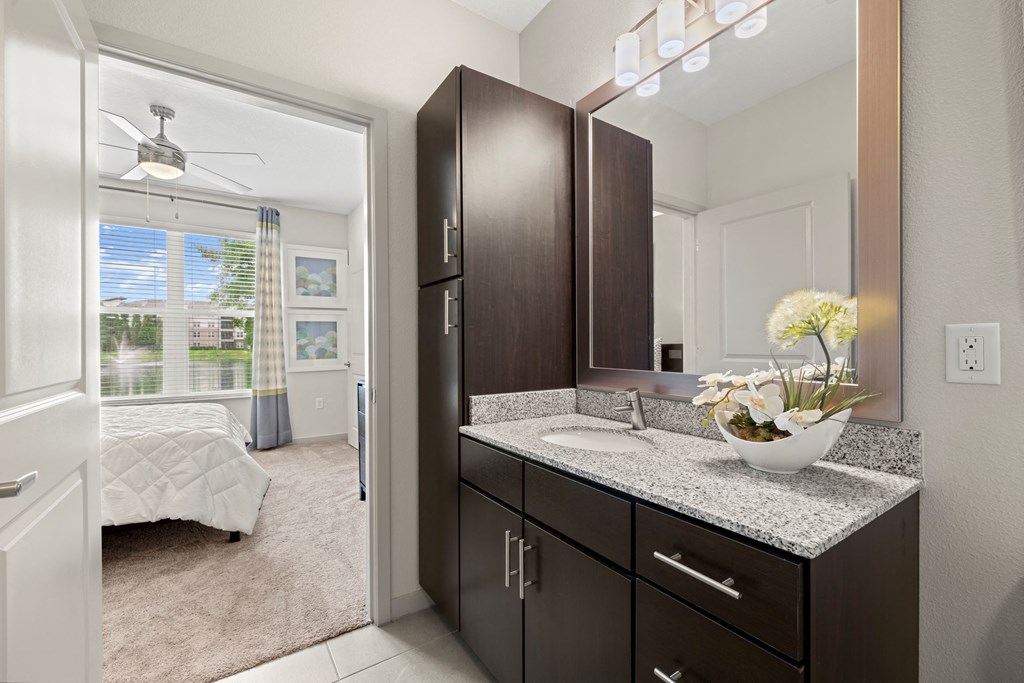 a bathroom with dark cabinets and a vanity with a sink at Pearce at Pavilion Luxury Apartments, Florida