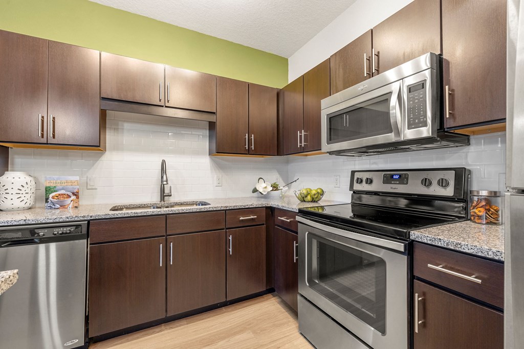 a kitchen with stainless steel appliances and wooden cabinets at Pearce at Pavilion Luxury Apartments, Riverview, Florida