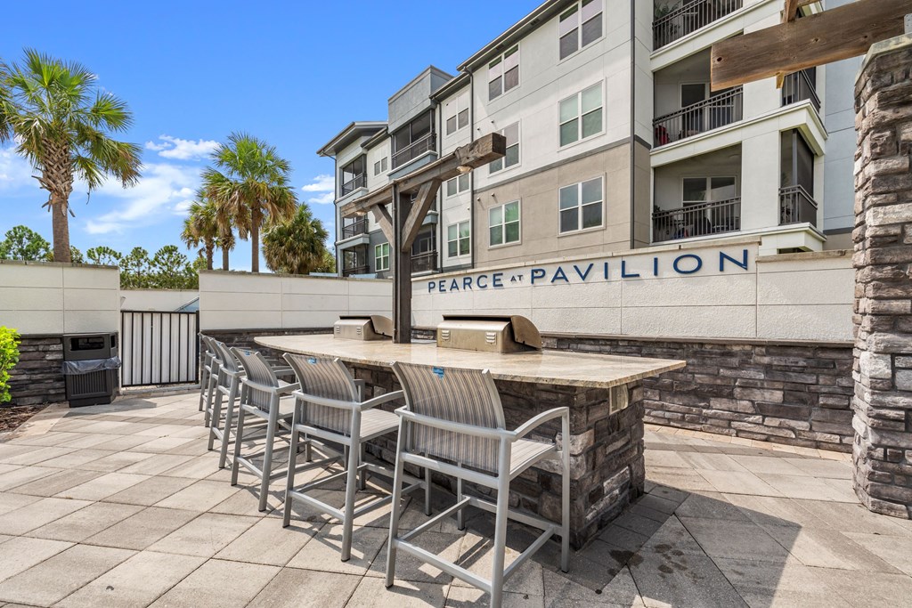 a patio with a bar and chairs in front of an apartment building at Pearce at Pavilion Luxury Apartments, Riverview, FL, Florida