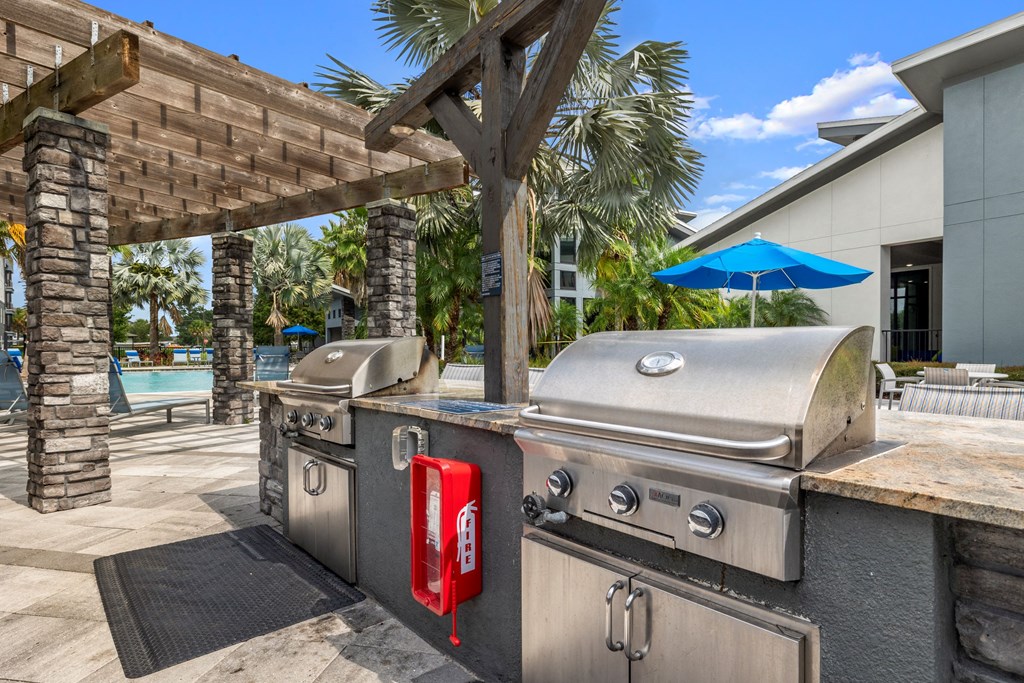 a backyard with two stainless steel barbecue grills and a picnic table at Pearce at Pavilion Luxury Apartments, Riverview, FL