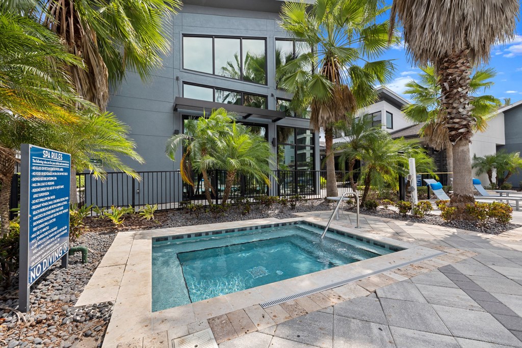 a swimming pool in front of a building with palm trees at Pavilion Luxury Apartments, Riverview, 33578