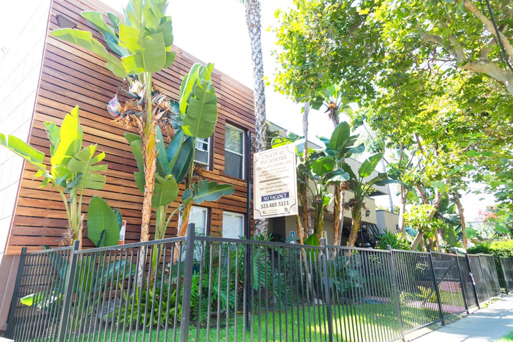 side view of building with leasing sign, gate, and grassy area.