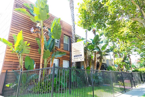 side view of building with leasing sign, gate, and grassy area.