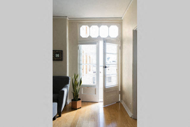 a living room with a black couch and a plant