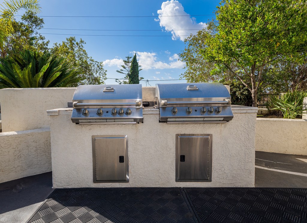two stainless steel barbecue grills on top of a white building