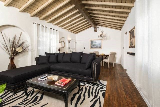 Villa Valentino 12 Living Room with a black studded couch and wooden ceiling with a seating area in the back