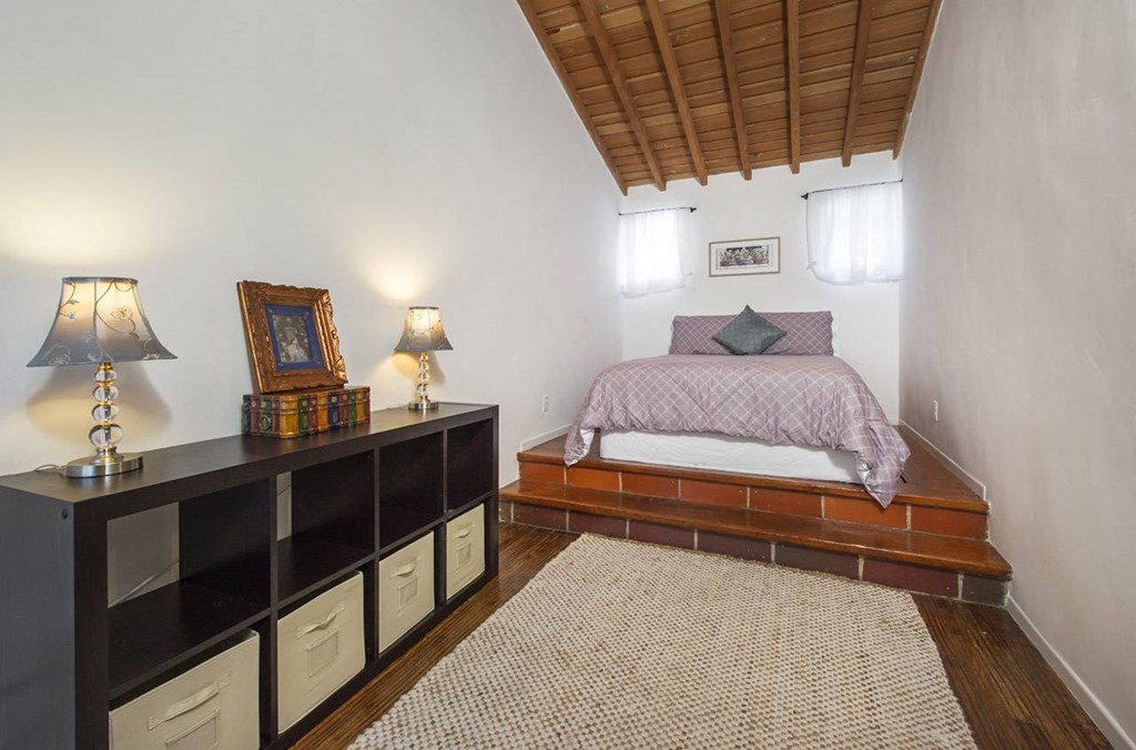 Villa Valentino 14 Second Bedroom with the bed on a raised section of the room with 2 windows and a black storage space