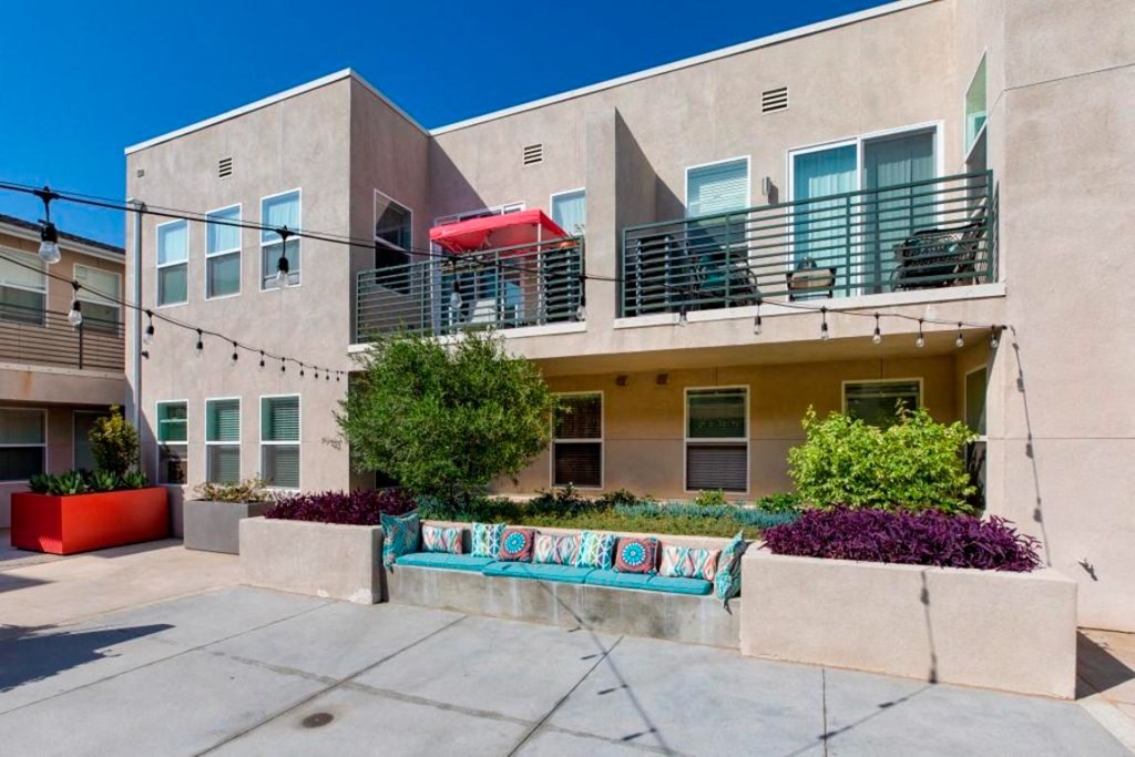 outdoor seating area with blue cushions and pillows with a view of the courtyard and building