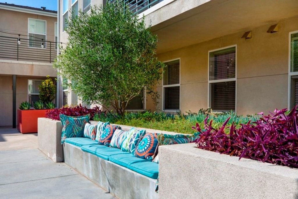 outdoor seating area with blue cushions and pillows and trees